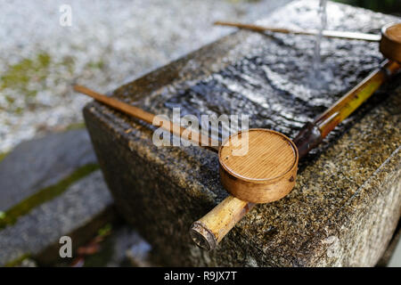 Traditional ancient stone well, a tsukubai (stone water basin) with bamboo ladle in japanese garden, Japan Stock Photo