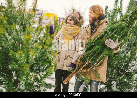 Theme is the symbol of Christmas and New Year holidays. Beautiful young Caucasian heterosexual couple buyer chooses, makes a purchase on the Christmas Stock Photo