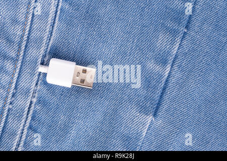 White USB cable in a denim pocket, USB cord with a denim pocket, the concept of communication and computer technology, social network Stock Photo