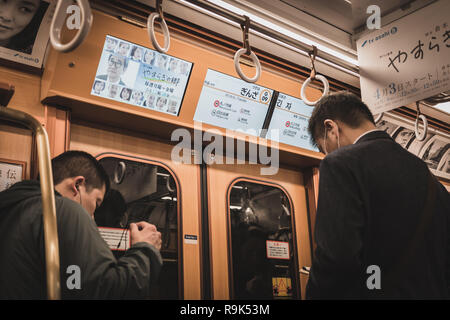 Two Men Waiting To Leave The Train On Tokyo Metro Ginza Line Train Arriving At Ginza Station Screen Showing The Station Information And Interchange Stock Photo Alamy