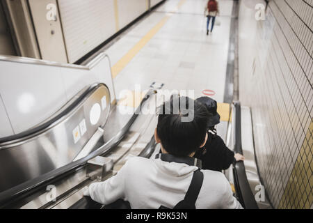 Close up back of a boy using escalator to access Tokyo Metro Station Stock Photo