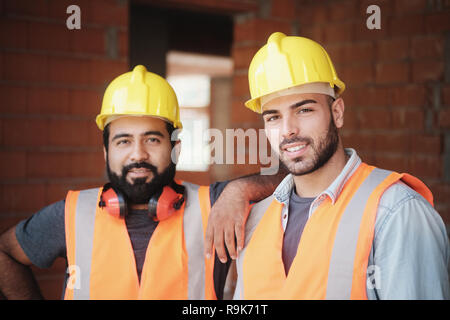 People working in construction site. Portrait of happy men at work in new house inside apartment building. Professional workers looking and smiling at Stock Photo