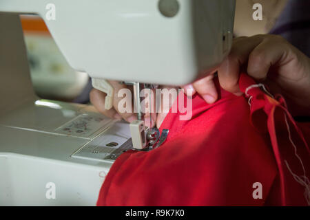 Woman seamstress working making clothes on a sewing machine. Stock Photo