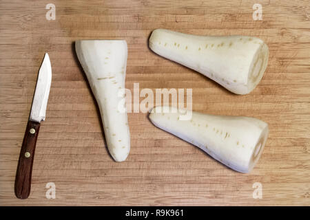 Parsnips and knife on wooden chopping board close up detail preperation for cooking vegetable view above Stock Photo