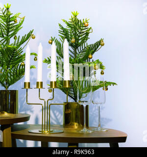 New year's interior. A small artificial Christmas tree with toys and candles. Glasses serving Stock Photo