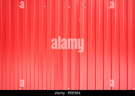 Texture of a metal fence from the profile of a red sheet with vertical lines. Stock Photo