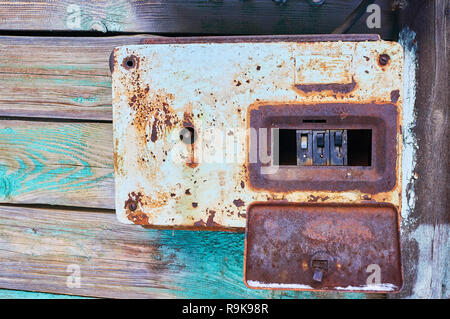 An old and rusty electric circuit breaker placed on a wall in a rusty metal box Stock Photo