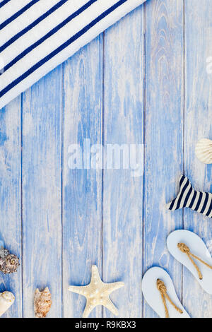 Creative flat lay concept of summer travel vacations. Top view of towel flip flops seashells and starfish on pastel blue wooden planks background with Stock Photo