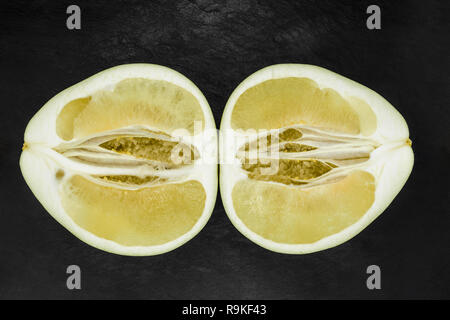 Top view of divided in the half pomelo fruit and placed on black stone background surface Stock Photo