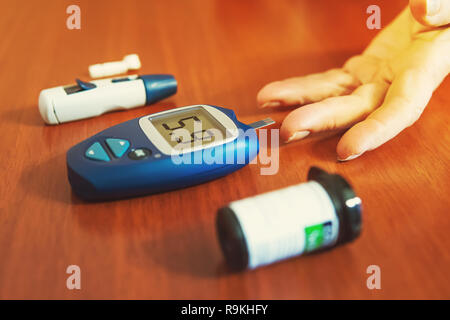 Woman testing for high blood sugar. Woman holding device for measuring blood sugar. drop of blood on finger close up Stock Photo