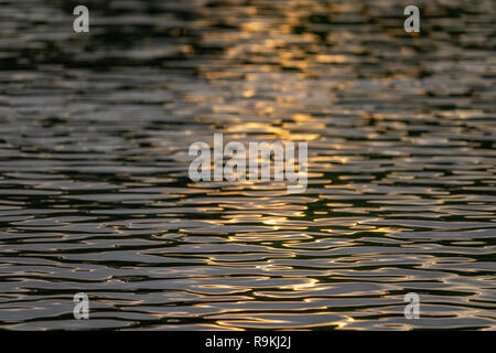 Setting sun reflecting on river water patterns Stock Photo