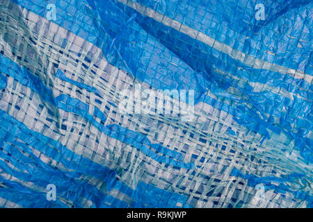 Macro-photo of very worn blue cheap Poly-Tarpaulin - exposed inner woven plastic fabric laminated with blue LDPE / Low-density Polyethylene. Stock Photo