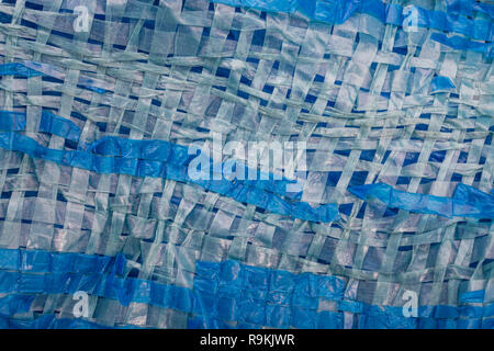 Macro-photo of very worn blue cheap Poly-Tarpaulin - exposed inner woven plastic fabric laminated with blue LDPE / Low-density Polyethylene. Stock Photo