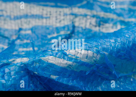 Macro-photo of very worn blue cheap Poly-Tarpaulin - exposed inner woven plastic fabric laminated with blue LDPE / Low-density Polyethylene. Stock Photo