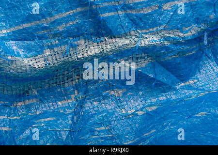 Macro-photo of very worn blue cheap Poly-Tarpaulin - exposed inner woven plastic fabric laminated with blue LDPE / Low-density Polyethylene. Stock Photo