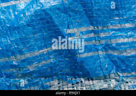 Macro-photo of very worn blue cheap Poly-Tarpaulin - exposed inner woven plastic fabric laminated with blue LDPE / Low-density Polyethylene. Stock Photo