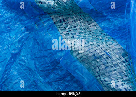 Macro-photo of very worn blue cheap Poly-Tarpaulin - exposed inner woven plastic fabric laminated with blue LDPE / Low-density Polyethylene. Stock Photo