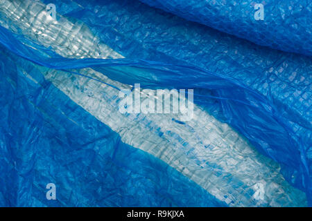 Macro-photo of very worn blue cheap Poly-Tarpaulin - exposed inner woven plastic fabric laminated with blue LDPE / Low-density Polyethylene. Stock Photo