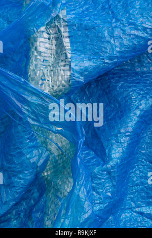 Macro-photo of very worn blue cheap Poly-Tarpaulin - exposed inner woven plastic fabric laminated with blue LDPE / Low-density Polyethylene. Stock Photo