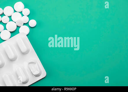 Blister and white tablets isolated on green background, conceptual image Stock Photo