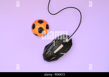 Soccer ball with computer mouse on violet background. Concept of videogames, eSports, sports betting and online gambling Stock Photo