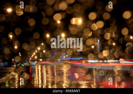 Main street at night seen through water droplets on car windshield after the rain Stock Photo