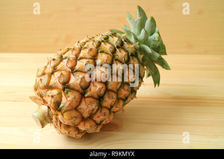 One fresh ripe pineapple whole fruit isolate on wooden background Stock Photo