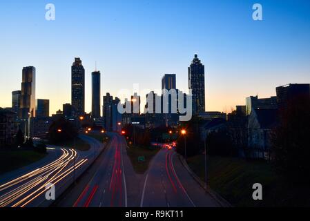 Atlanta downtown skyline lit up at sunset, along busy highway at rush hour, in Atlanta, Georgia, USA Stock Photo