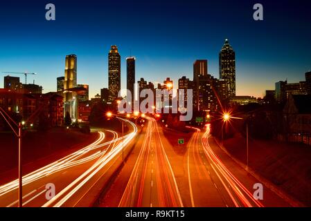 Atlanta downtown skyline lit up at sunset, along busy highway at rush hour, in Atlanta, Georgia, USA Stock Photo