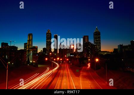 Atlanta downtown skyline lit up at sunset, along busy highway at rush hour, in Atlanta, Georgia, USA Stock Photo