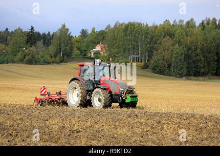 Salo, Finland - September 21, 2018: Farmer cultivates harvested stubble field with Valtra tractor and Horsch Terrano 3 FX cultivator in autumn. Stock Photo