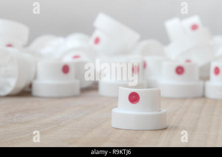Several new plastic nozzles from a paint sprayer that lie on a wooden surface against a gray wall background. The concept of street art and graffiti Stock Photo