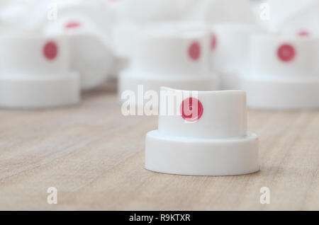 Several new plastic nozzles from a paint sprayer that lie on a wooden surface against a gray wall background. The concept of street art and graffiti Stock Photo