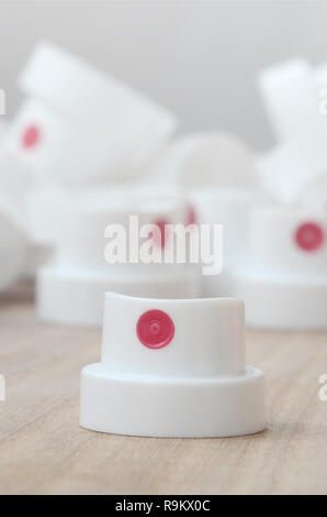 Several new plastic nozzles from a paint sprayer that lie on a wooden surface against a gray wall background. The concept of street art and graffiti Stock Photo