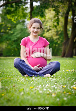 Pregnant woman relaxing in the park Stock Photo