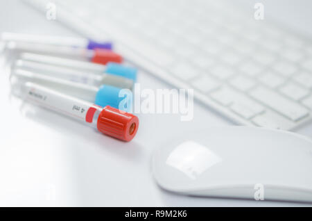 Medicine bottles for samples next to computer keyboard and mouse in medicine, closeup on white background Stock Photo