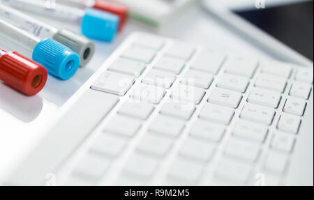 Medicine bottles for samples next to computer tablet and computer keyboard in medicine, on white background Stock Photo