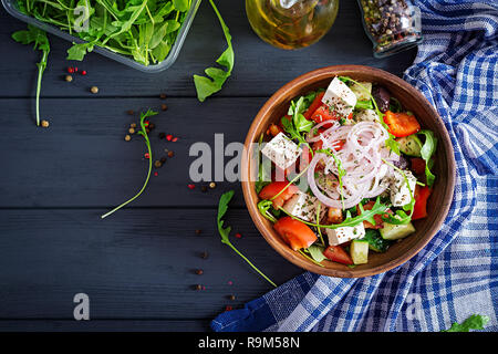 Greek salad with fresh tomato, cucumber, red onion, basil, feta cheese, black olives and Italian herbs. Top view Stock Photo
