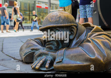 Statue of a man peaking out from under a manhole cover in Bratislava, Slovakia on August 2018