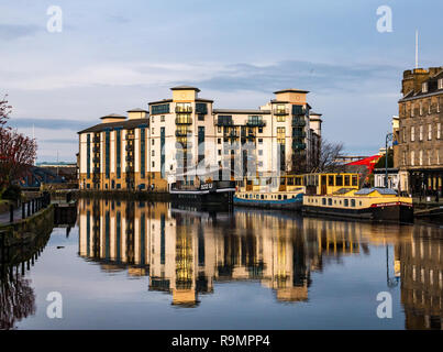 The Shore, Leith, Edinburgh, Scotland, UK. 26th Dec, 2018.  UK Weather: A brighter Boxing Day ends with sun reflected off the windows of apartments of the modern development of Queen's Quay on the riverbank of the Water of Leith, and buildings and barges colourfully reflected in the water Stock Photo