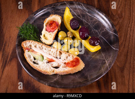 Close-up photo of a sandwich. Sandwich with meet, prosciutto, salami, salad, vegetables, lettuce, tomato, onion and mustard on a fresh sliced rye brea Stock Photo