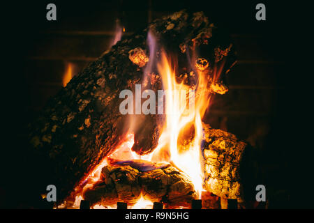 Cozy fireplace. Wood logs burning, dark background, relaxation and warm home, closeup view with details Stock Photo