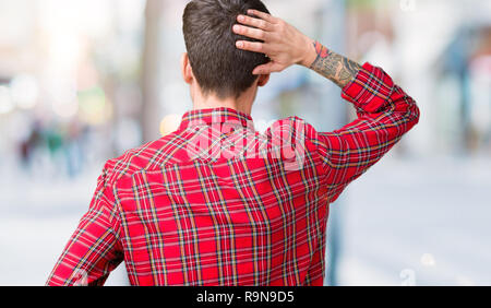 Young handsome man wearing glasses over isolated background Backwards thinking about doubt with hand on head Stock Photo