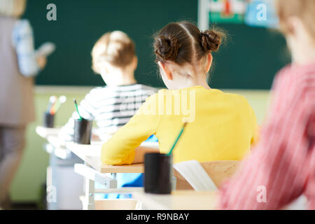 School students writing in workbooks at lesson Stock Photo