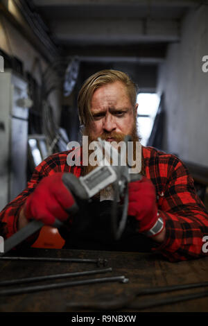 Frowning worker measuring steel detail Stock Photo