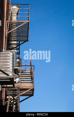 Fire escape rusty stairs and ladder, in metal, on a typical North American old brick building from Montreal, Quebec, Canada. These stairs, made for em Stock Photo