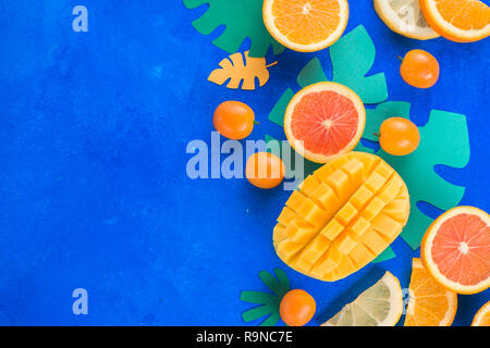 Citrus fruits, mango, oranges, kumquat, and other tropical fruits vibrant blue background with copy space. Exotic fruits close-up. Stock Photo