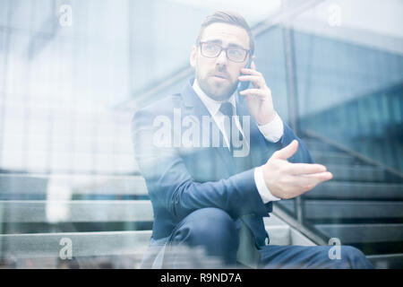 Business man sitting on steps talking smartphone  Stock Photo