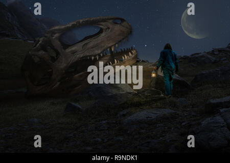 Man exploring creepy mountain landscape with a lamp and finding a giant dinosaur skull in the middle of nowhere Stock Photo