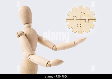 Business and design concept - wooden mannequin with surreal jigsaw gear isolated on white background. the symbol of leadership, communication and succ Stock Photo